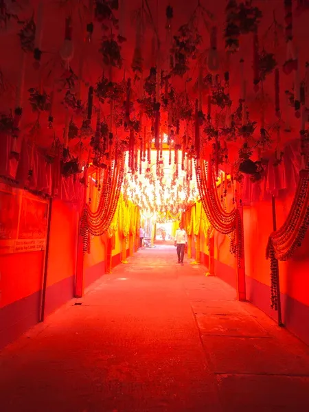 Festivals & Observances: A long corridor decorated in red and orange drapery and garlands for a festival